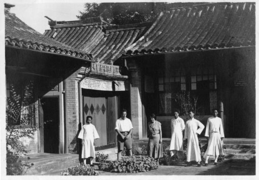 A photograph of four Chinese men and women posing with Annette and Jacob Rabinowitz outside of a residential building in Beijing, China.