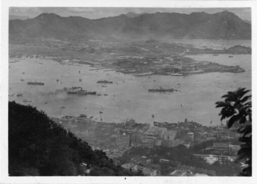 Photograph taken from the mountains looking down on boats in Victoria Harbor and the buildings of Hong Kong